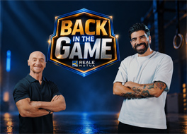 Primo piano di Gianluca Gazzoli e Jury Chechi sorridenti in una palestra e il logo del format 'Back in the game' e il logo di Reale Mutua