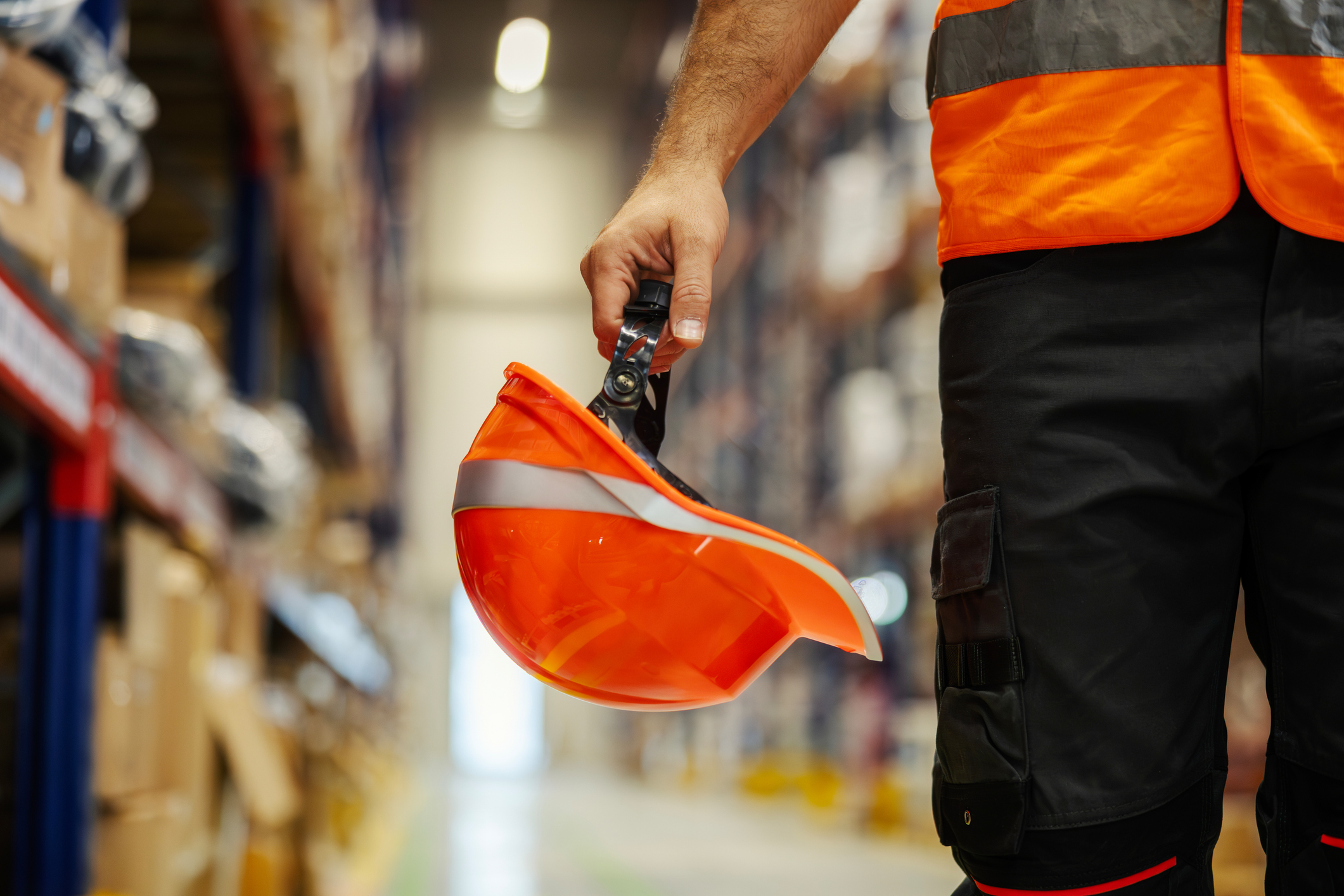Primo piano della mano di un operaio che tiene in mano il suo caschetto da lavoro