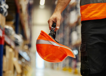 Primo piano della mano di un operaio che tiene in mano il suo caschetto da lavoro